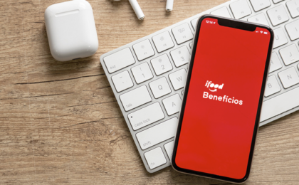 celular com a tela vermelha e logo do ifood benefícios na cor branca